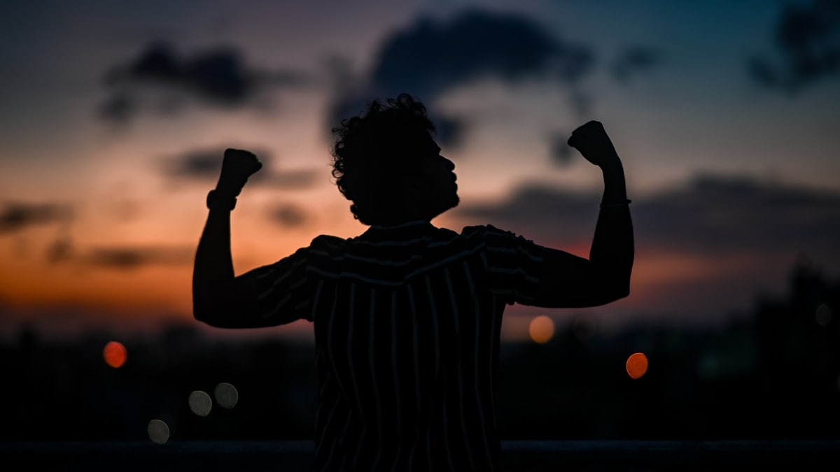 a silhouette of a man raising his arms in the air